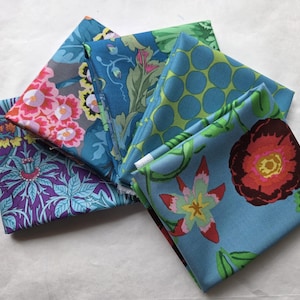 May include: A collection of folded fabric squares with various floral patterns. The fabrics feature designs in shades of blue, green, pink, and purple. The patterns include large flowers, dots, and botanical motifs.