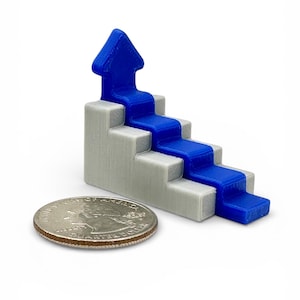 May include: A 3D-printed gray staircase with a blue arrow pointing upwards. A quarter coin is next to the staircase for size comparison. The staircase has four steps and a blue arrow at the top.