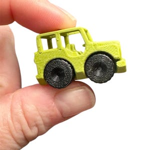 Peut inclure: Un petit jouet jeep vert citron avec des roues noires. La jeep a un design détaillé, comprenant un porte-bagages et des détails intérieurs. Les roues ont un motif texturé. Le jouet est tenu dans la main d'une personne.