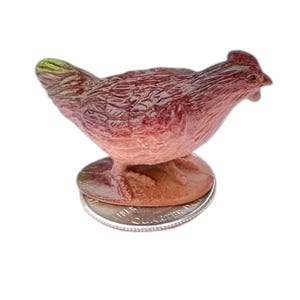 May include: A small, hand-painted ceramic figurine of a brown and white chicken. The figurine is standing on a US quarter for scale.