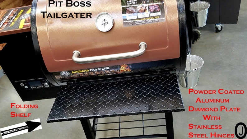 May include: A brown and black Pit Boss Tailgater smoker with a stainless steel handle and a black diamond plate shelf. The smoker has a digital control panel and an automated feed system. The shelf is powder coated aluminium with stainless steel hinges.