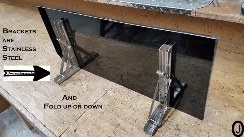 May include: A black rectangular panel with two stainless steel folding brackets. The brackets are attached to the panel and can be folded up or down. The text "BRACKETS ARE STAINLESS STEEL" is visible in the image. The text "joecarparts" is also visible in the image.