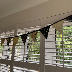 Bee Lovers Honey Hive Inspirational Quote Bee Kind Sunflower Black and Yellow Cotton Fabric Bunting by Bluebell Bunting. Small bunting in a window display, draped from the lintel, against white shutters.