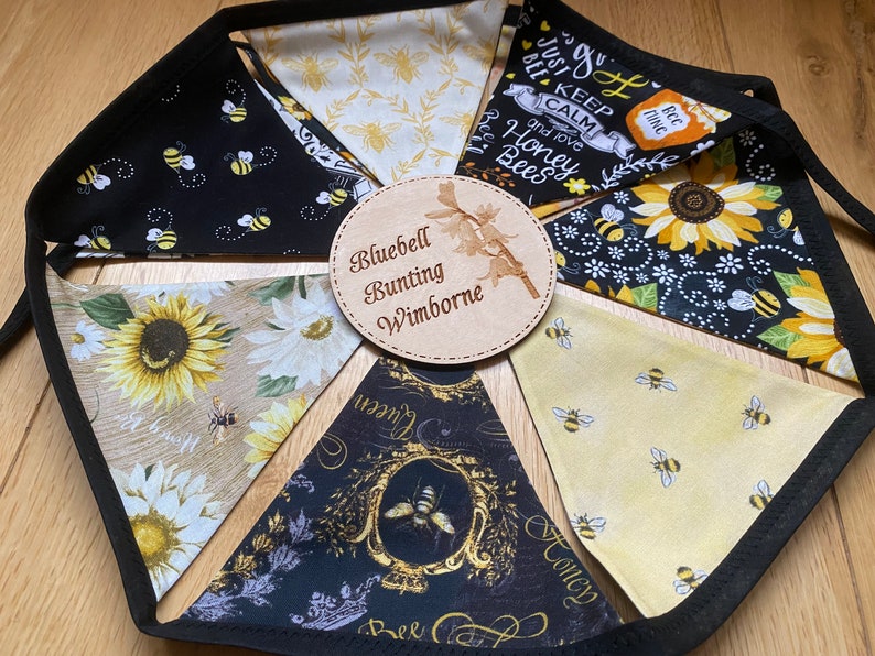 Bee Lovers Honey Hive Inspirational Quote Bee Kind Sunflower Black and Yellow Cotton Fabric Bunting by Bluebell Bunting. Small sized flags in a circle on the floor so that all flags can be seen closely at once.