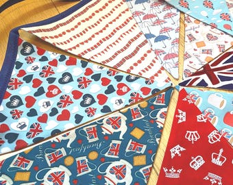 May include: A fabric bunting banner featuring triangular flags with various British-themed patterns including Union Jack hearts, crowns, teapots, umbrellas, and hot air balloons, all connected by a dark blue fabric binding tape along the top edge.