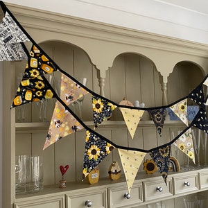 Bee Lovers Honey Hive Inspirational Quote Bee Kind Sunflower Black and Yellow Cotton Fabric Bunting by Bluebell Bunting. Medium and small buntings on a kitchen dresser. Colour scheme is black and yellow.