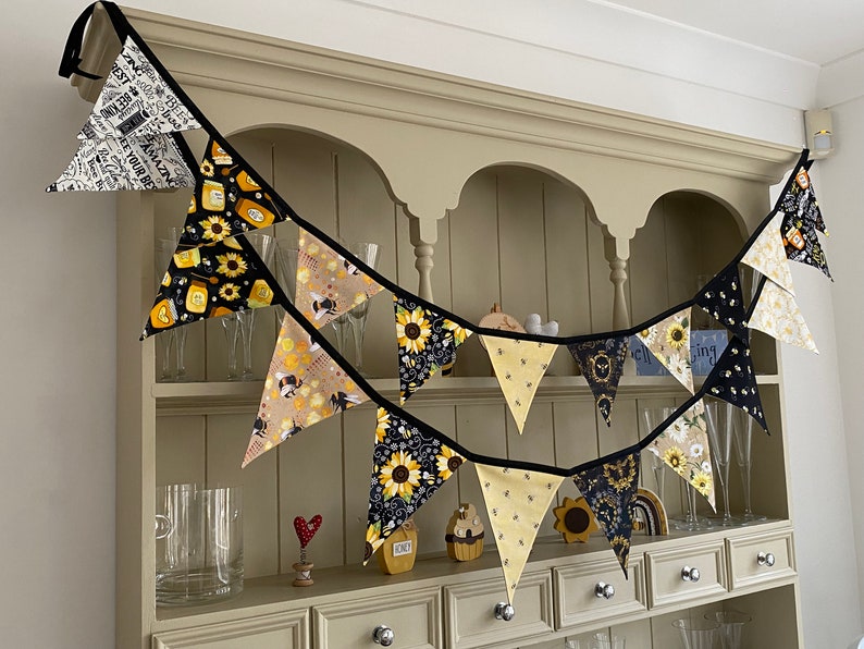 Bee Lovers Honey Hive Inspirational Quote Bee Kind Sunflower Black and Yellow Cotton Fabric Bunting by Bluebell Bunting. Medium and small buntings on a kitchen dresser. Colour scheme is black and yellow.