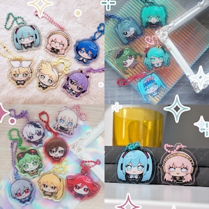 May include: A selection of anime-style character keyrings. Each keyring features a different character with unique hair colours and outfits. The charms are clear acrylic with metal chains and clasps. The characters are in a chibi style.