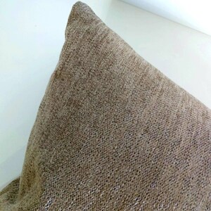 May include: A close-up of a brown throw pillow with a textured fabric.