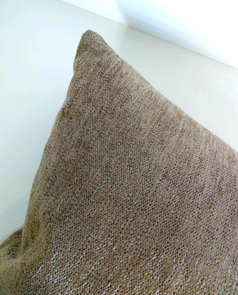 May include: A close-up of a brown throw pillow with a textured fabric.