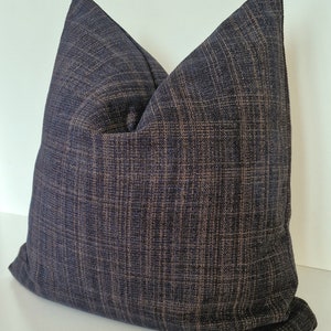 May include: A dark blue and brown patterned throw pillow with a textured fabric.