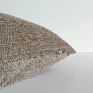 May include: A brown throw pillow with a zipper closure.