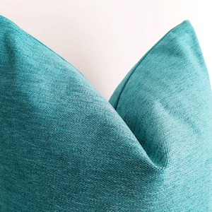 May include: A teal blue throw pillow with a textured fabric.