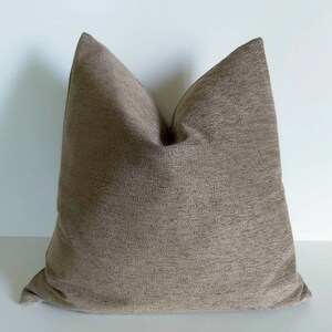 May include: A brown square pillow with a textured fabric.