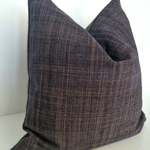 May include: A dark blue throw pillow with a textured woven fabric. The pillow is square shaped and has a subtle sheen.