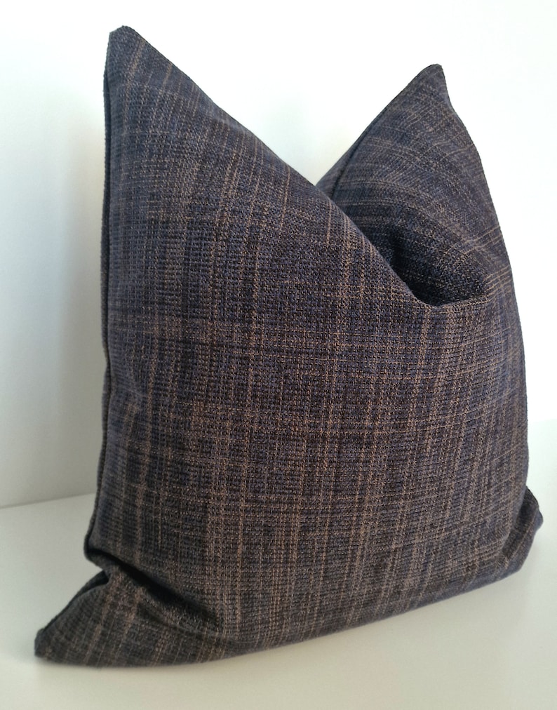 May include: A dark blue throw pillow with a textured woven fabric. The pillow is square shaped and has a subtle sheen.