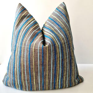 May include: A decorative pillow with a brown background and vertical stripes in blue, light blue, and yellow. The pillow has a textured appearance and is likely made of fabric.