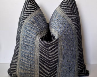 May include: A decorative throw pillow with a geometric pattern in shades of blue and gray. The pillow has a chevron design with a textured fabric.