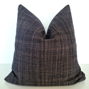 May include: A dark blue throw pillow with a subtle woven texture. The pillow is made of a soft, comfortable fabric and has a square shape.