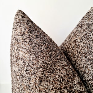 May include: Two brown and white patterned throw pillows with a textured fabric.