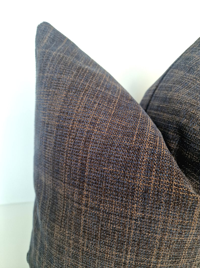 May include: Two dark blue throw pillows with a subtle brown woven pattern. The pillows are made of a soft, textured fabric.