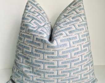 May include: A decorative throw pillow with a geometric pattern in shades of blue and beige. The pillow is made of a soft, textured fabric.