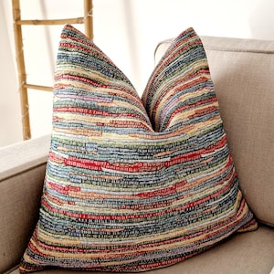 May include: A colourful striped throw pillow with a woven texture. The pillow is made of a variety of colours, including red, green, blue, and yellow.