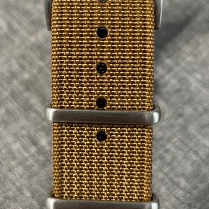 K&ouml;nnte beinhalten: Ein goldfarbenes Uhrenarmband mit einer silbernen Schlie&szlig;e und drei Halteschlaufen.