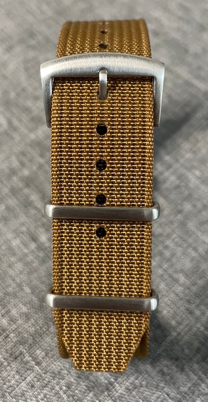 K&ouml;nnte beinhalten: Ein goldfarbenes Uhrenarmband mit einer silbernen Schlie&szlig;e und drei Halteschlaufen.