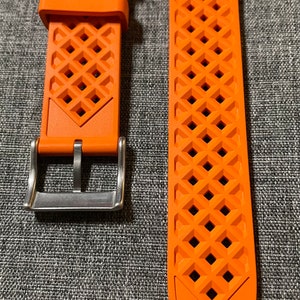 Puede incluir: Dos correas de reloj naranjas con un patr&oacute;n de diamante y el n&uacute;mero "22" impreso en ellas. La correa de la izquierda tiene una hebilla plateada.