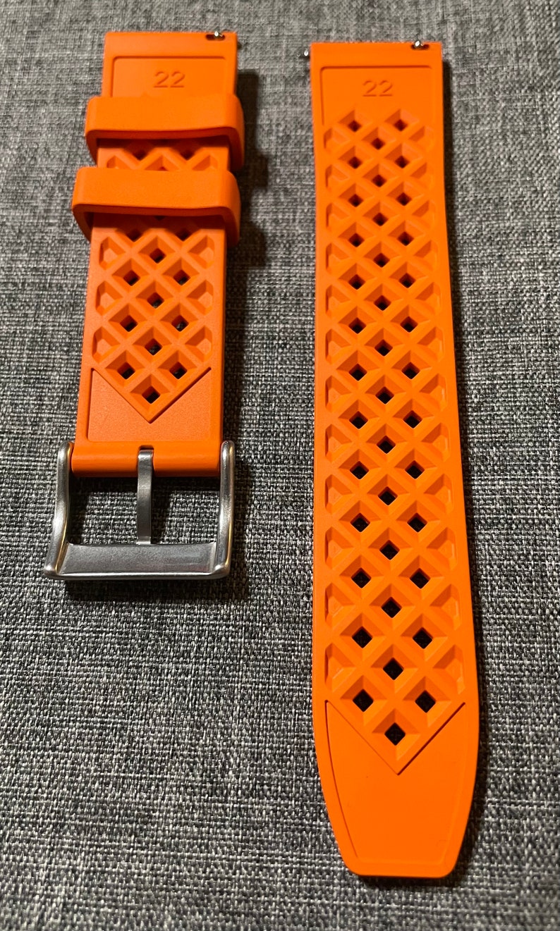 Puede incluir: Dos correas de reloj naranjas con un patr&oacute;n de diamante y el n&uacute;mero "22" impreso en ellas. La correa de la izquierda tiene una hebilla plateada.