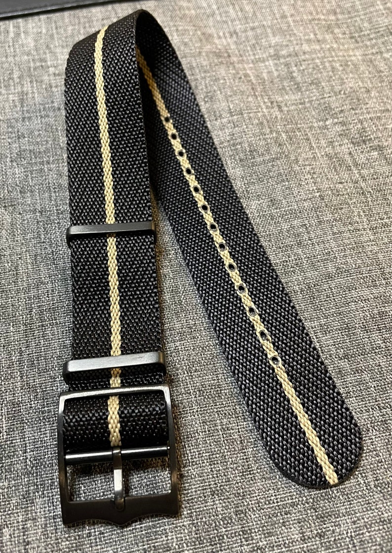 May include: Black watch strap with a white stripe down the center. The strap has a black buckle.
