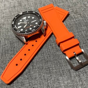 以下が含まれることがあります： オレンジ色のシリコン製腕時計ストラップとステンレススチール製のバックル。ストラップは、ラグ幅20mmの腕時計用に設計されています。