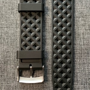 Puede incluir: Dos correas de reloj negras con un patr&oacute;n de diamante texturizado. Ambas correas est&aacute;n etiquetadas con "22 mm".