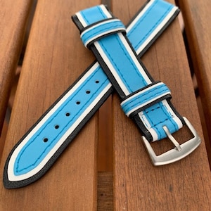 May include: A blue and white striped leather watch strap with black stitching and a silver buckle.