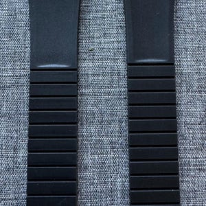 Puede incluir: Dos correas de reloj negras con la marca 22. Las correas est&aacute;n hechas de un material flexible y tienen un dise&ntilde;o segmentado. Se muestran sobre un fondo gris texturizado.