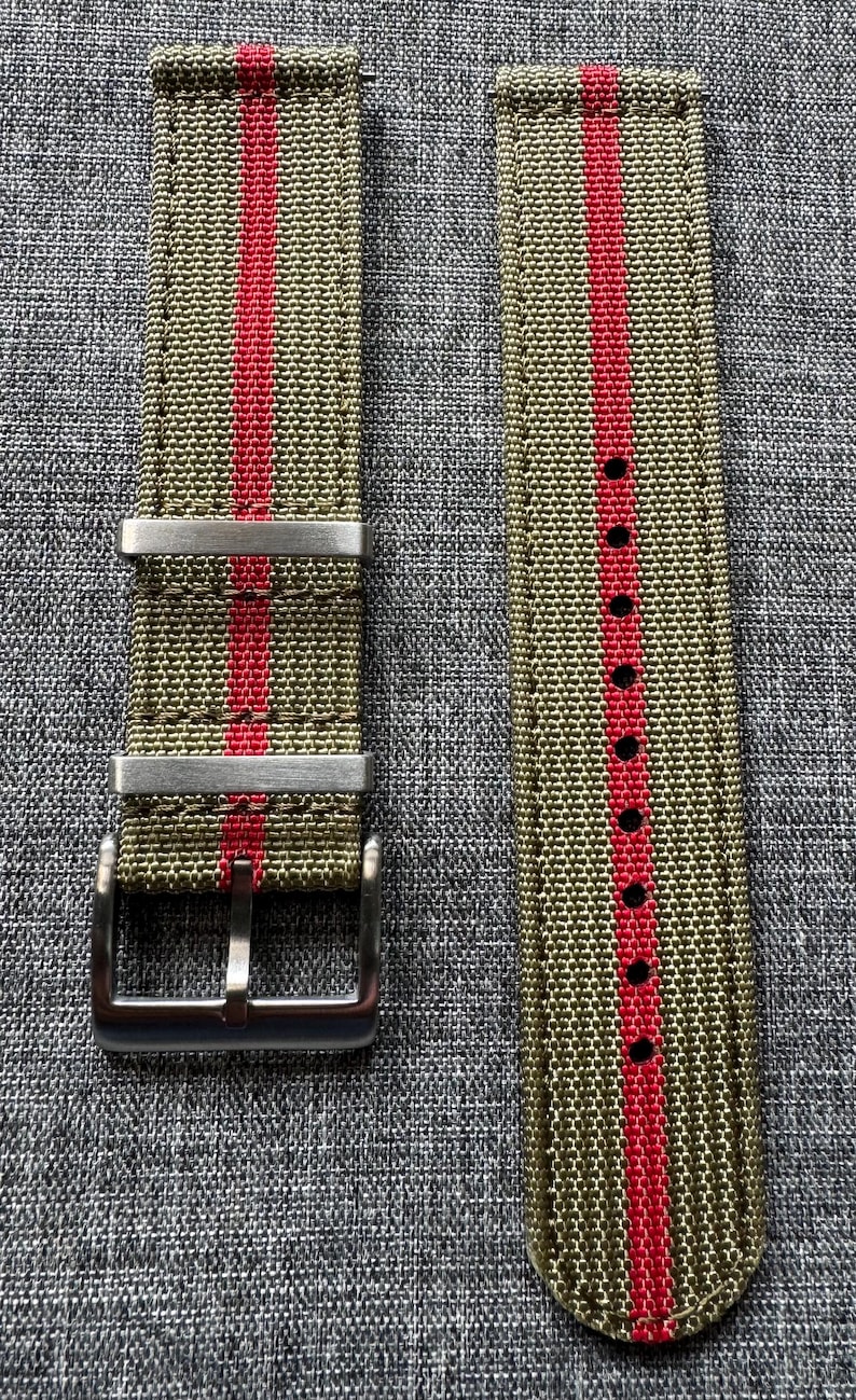 May include: A green and red striped watch strap with a silver buckle.
