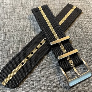 May include: Black watch strap with two white stripes and a silver buckle.
