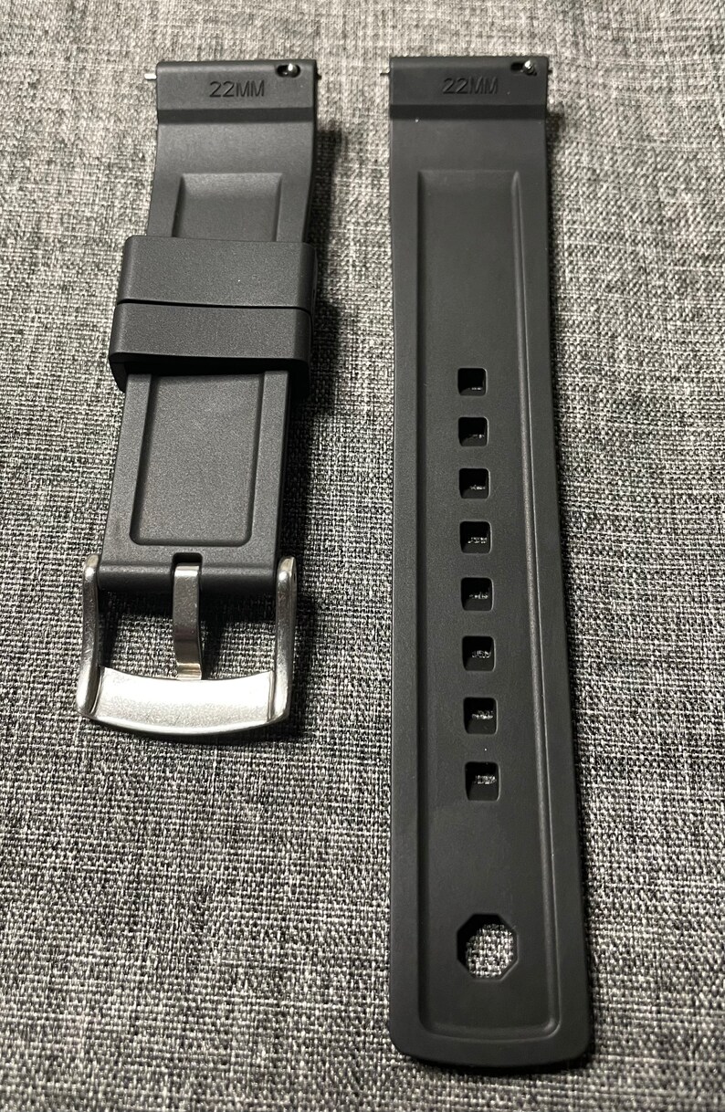 May include: Two black watch straps with silver buckles. The straps are 22mm wide and have a textured surface. One strap has a row of holes for adjusting the size.