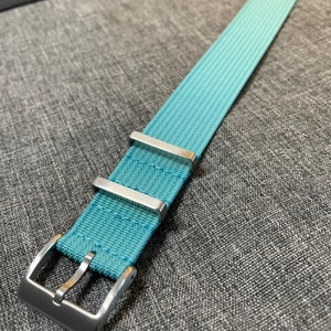 May include: A light blue watch strap with silver buckle and keepers.