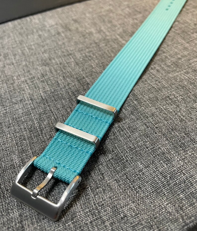 May include: A light blue watch strap with silver buckle and keepers.