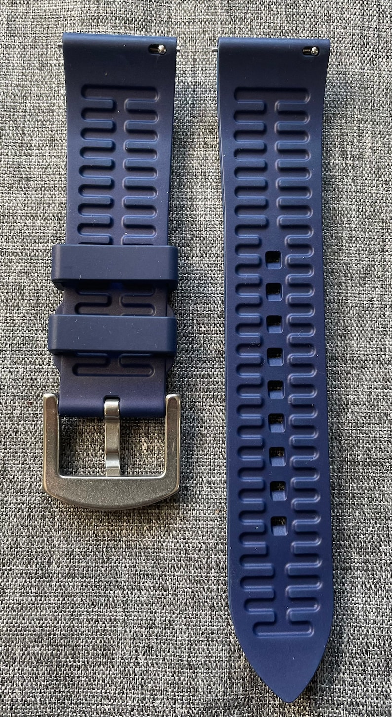 Puede incluir: Correa de reloj azul marino de dos piezas con hebilla plateada. La correa est&aacute; hecha de un material flexible con un dise&ntilde;o texturizado y acanalado. Dise&ntilde;ada para un reloj, se muestra sobre una superficie gris.