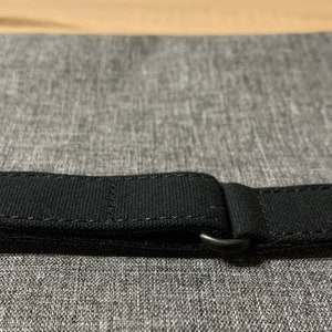 May include: Black watch strap with a buckle and stitching.