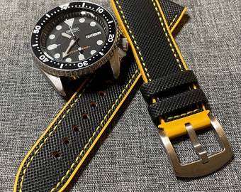 May include: Black watch strap with yellow stitching. The strap is made of a textured material and has a stainless steel buckle.