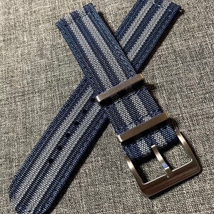 May include: A blue and gray striped watch strap with a silver buckle.