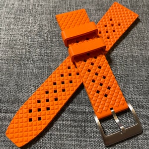 Puede incluir: Correa de reloj naranja con un patr&oacute;n de diamante y una hebilla plateada.