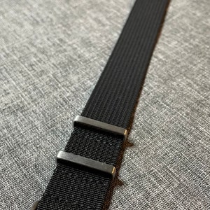 May include: Black watch strap with silver buckle and two silver keeper loops.