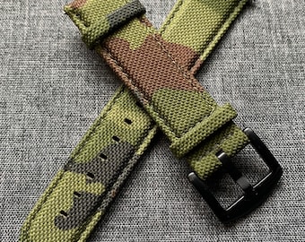 May include: A green, brown, and black camouflage patterned watch strap with a black buckle.