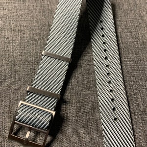 May include: A black and white striped watch strap with a silver buckle.