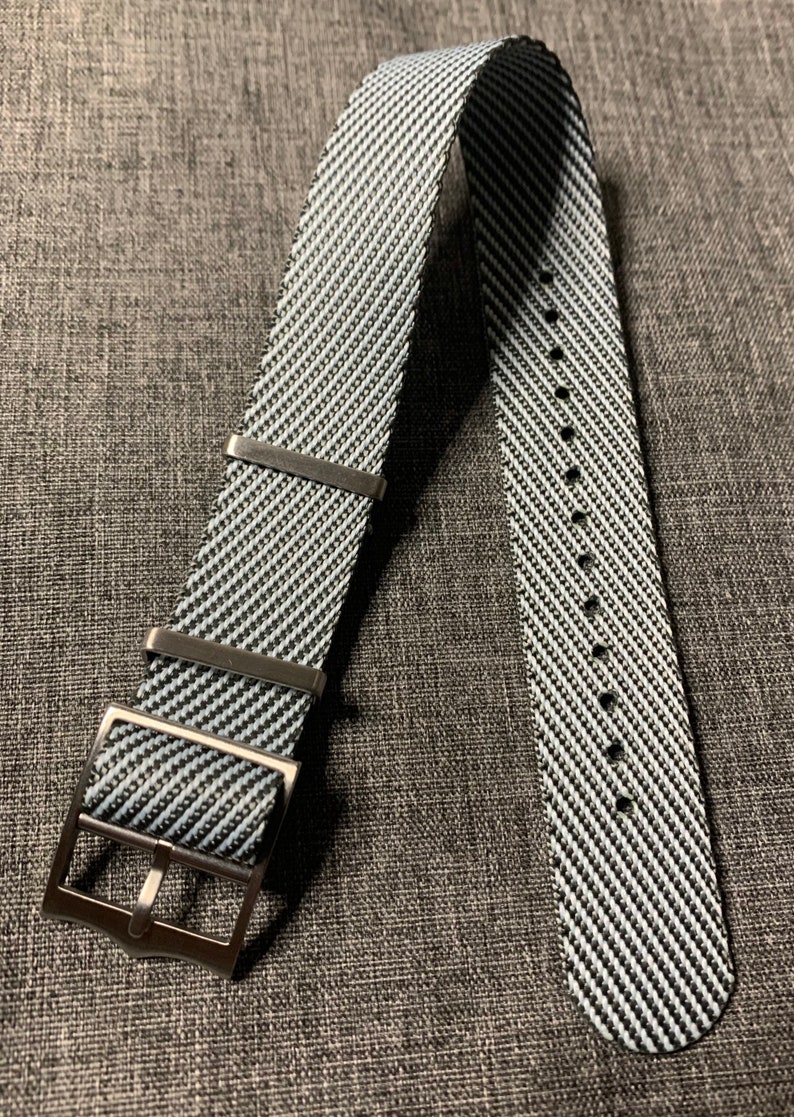 May include: A black and white striped watch strap with a silver buckle.